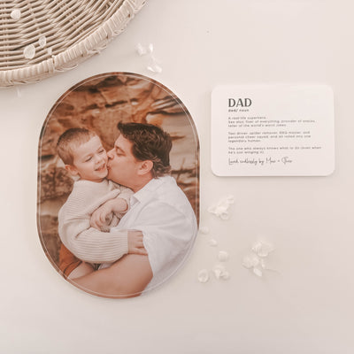Oval photo plaque with a father and child photo on a white surface with decorative elements.