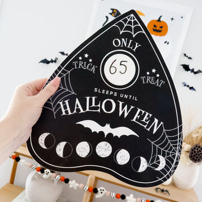 Halloween countdown sign with decorative elements on a shelf.
