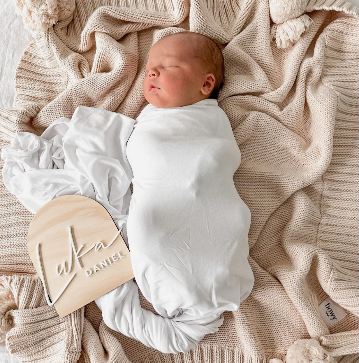 Newborn photography capturing precious moments of a baby's first days with wooden name plaque